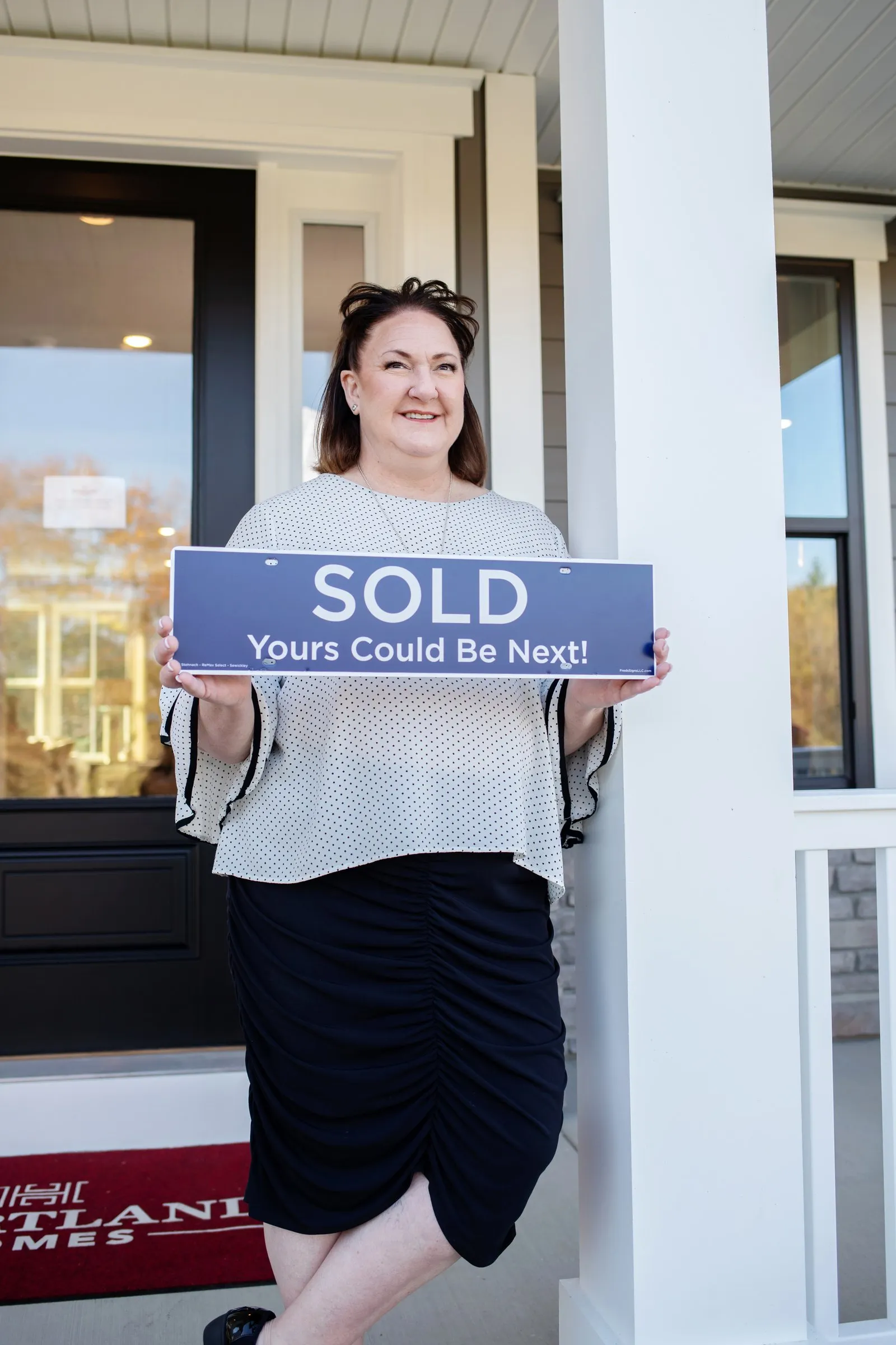 Jill Stehnach holding a SOLD sign on a front porch