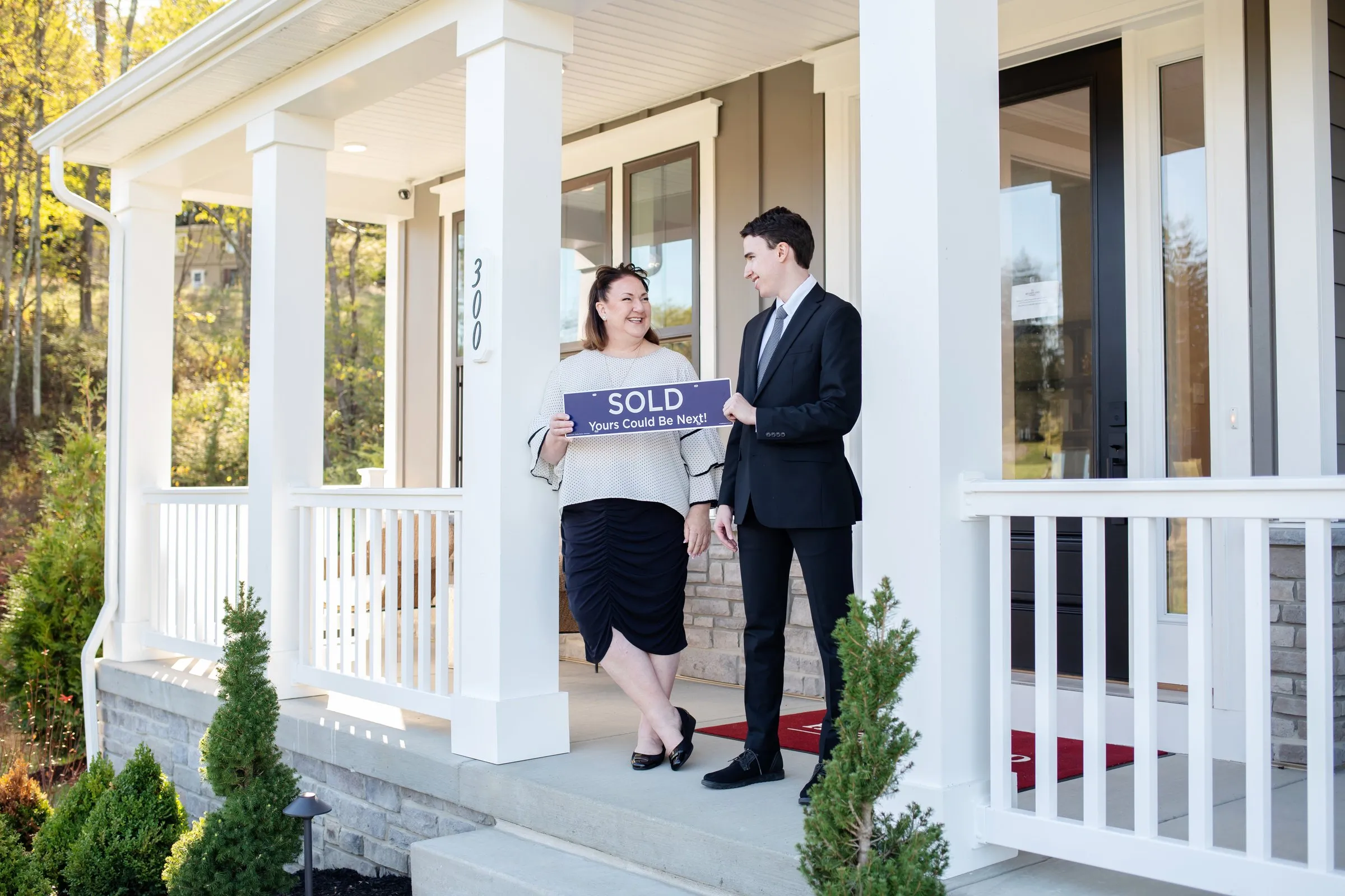 Jill and Matt Stehnach on a front porch with a SOLD sign